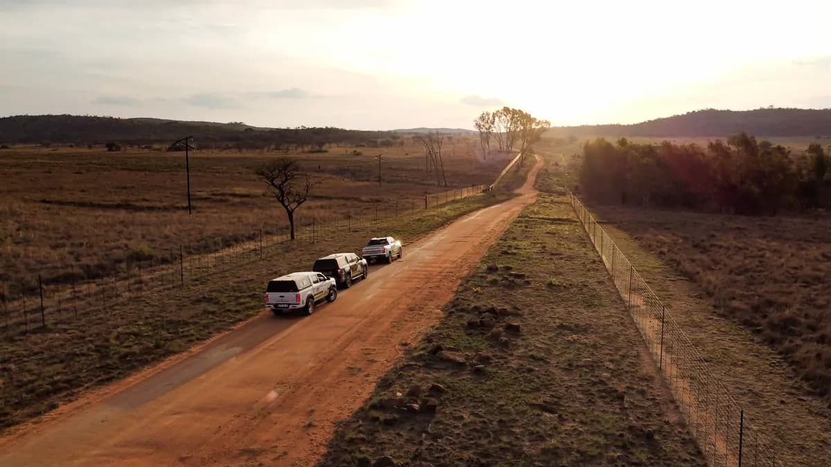 Three bakkies from the Seven7 Drive convoy, including the Changan Hunter, on a gravel road at sunrise